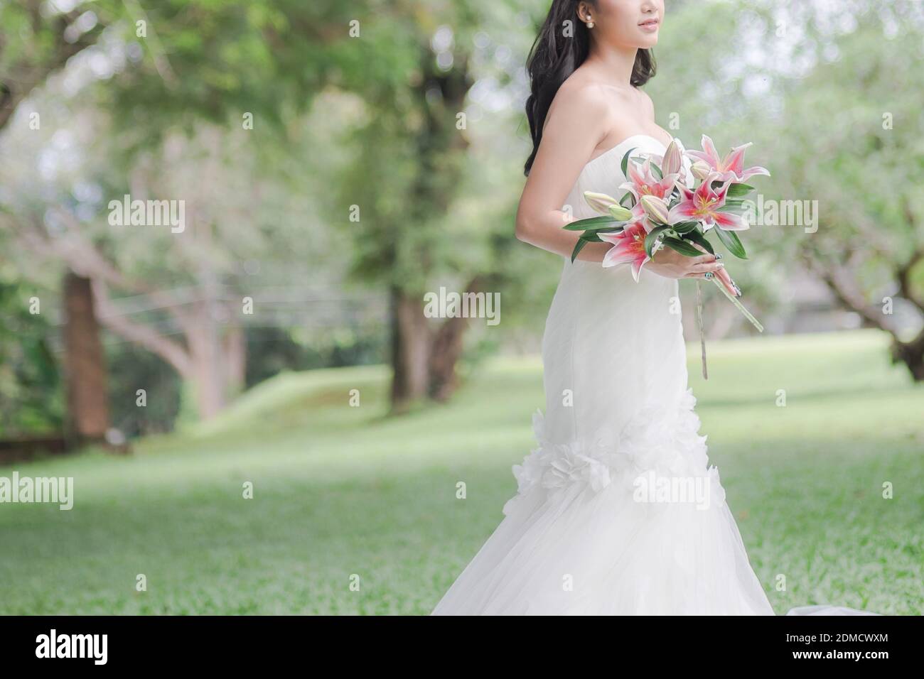 Midsection Of Smiling Bride Holding Flowers While Standing Outdoors Stock Photo