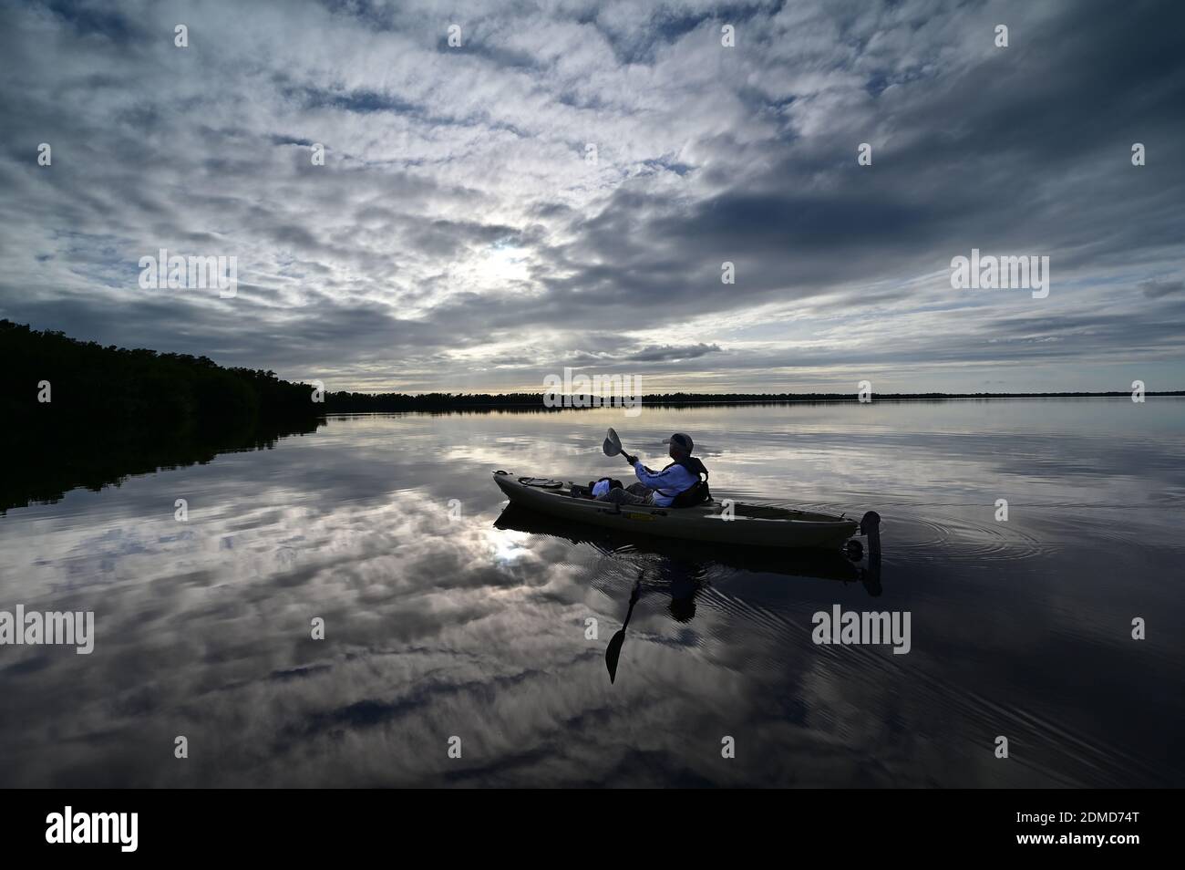 Everglades National Park, Florida - December 12, 2020 - Active senior kayaks at sunset under dramatic winter cloudscape in Coot Bay. Stock Photo
