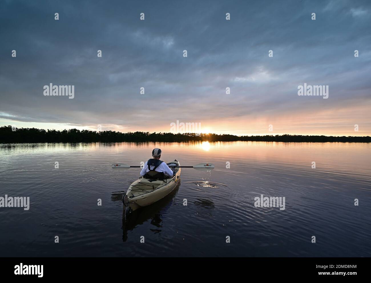 Everglades National Park, Florida - December 12, 2020 - Active senior kayaks at sunset under dramatic winter cloudscape in Coot Bay. Stock Photo