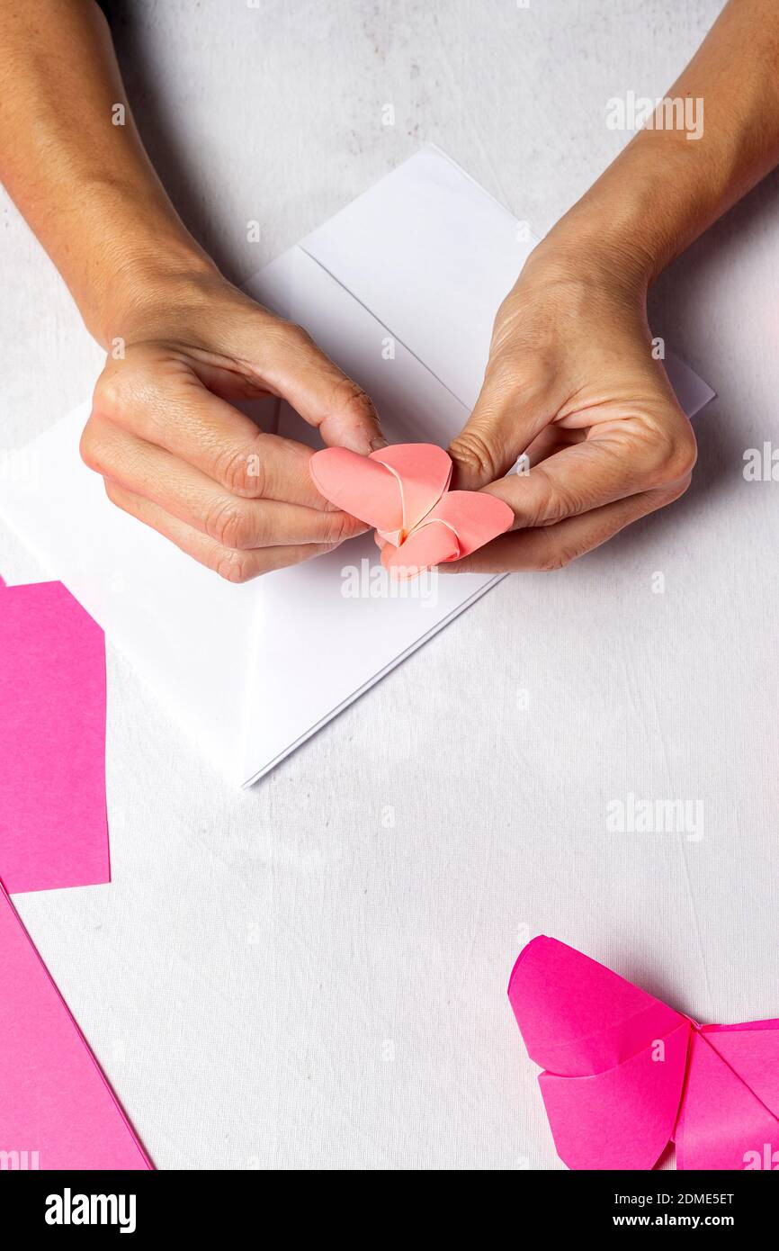 Woman hands making origami animals out of paper from above. Over white  table. Flat lay Stock Photo - Alamy