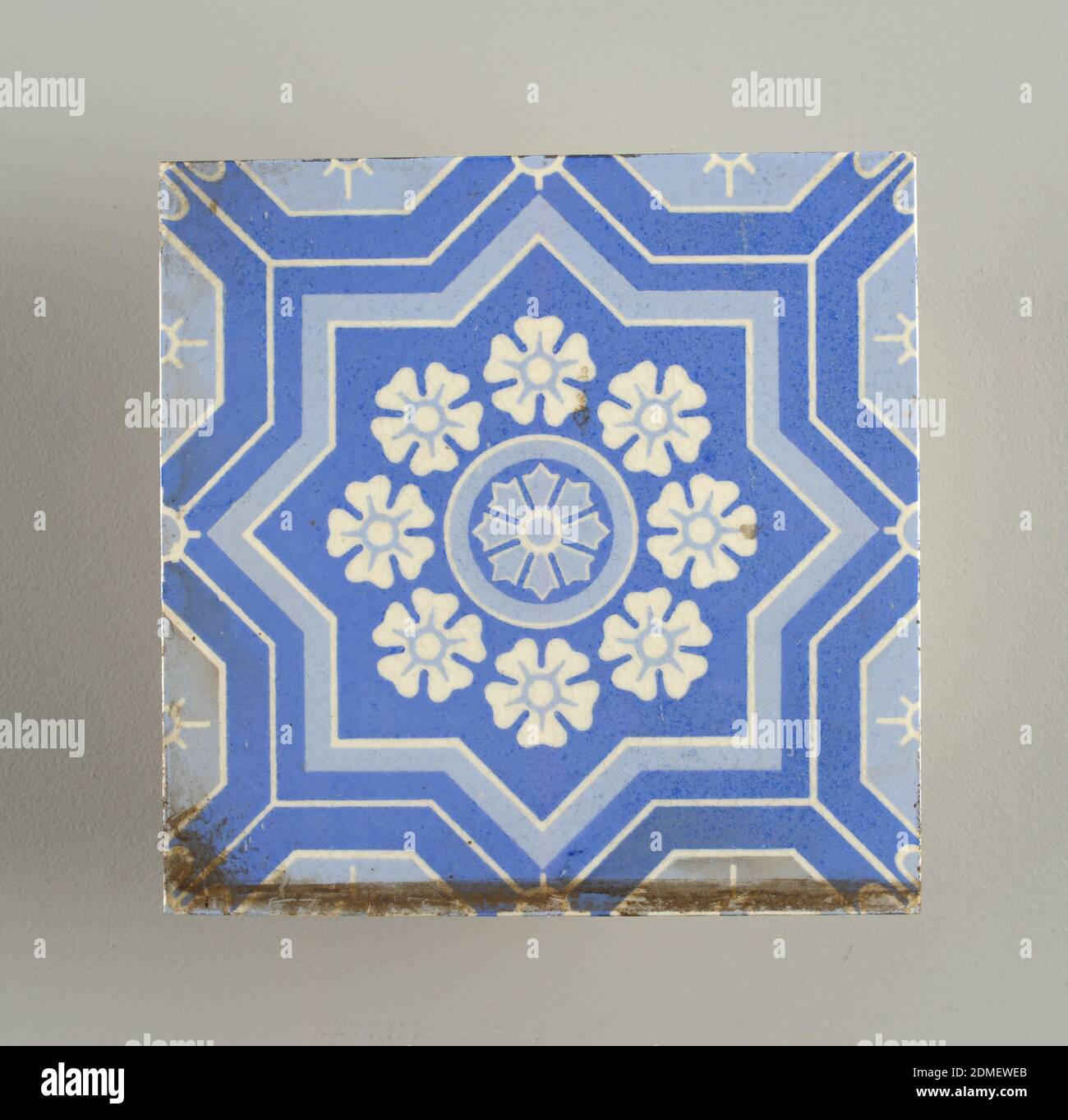 Tile, Stenciled and glazed earthenware, Square tile of white clay, overglaze with stenciled flower inside eight pointed star in two shades of blue., USA, ca. 1900, tiles, Decorative Arts, Tile Stock Photo