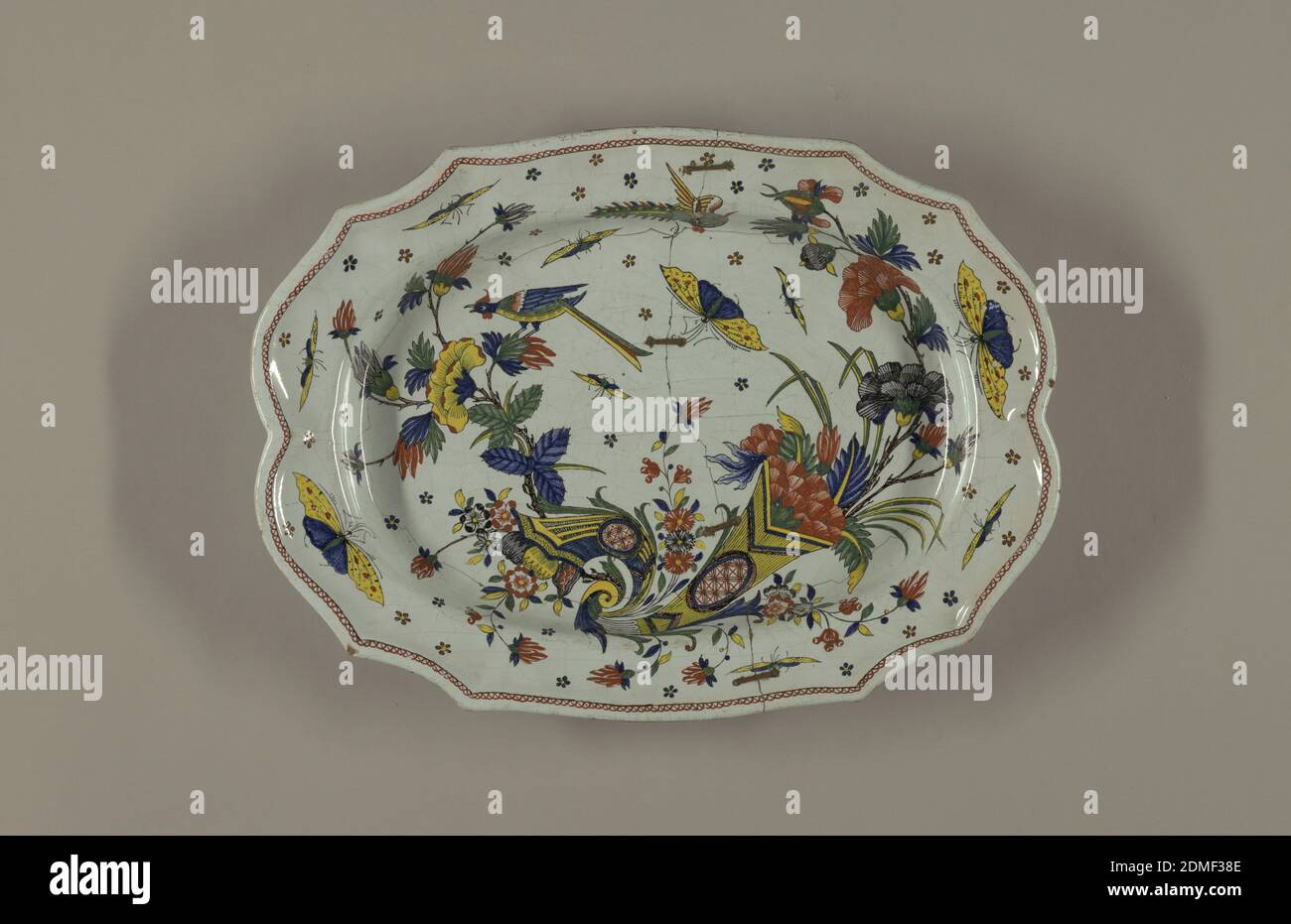 Platter, Tin-glazed earthenware, Irregular scalloped border, oval cavetto. Decoration in Chinese style. Double cornucopia with flowers, large insects and a long-tailed bird, possibly Sinceny, France, possibly Rouen, France, mid- 18th century, ceramics, Decorative Arts, Platter Stock Photo