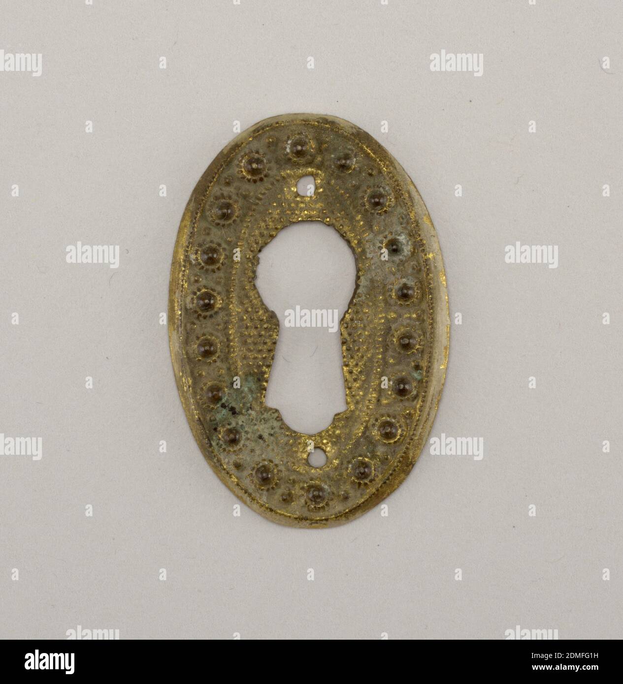 Escutcheon, Brass, Vertical ellipse. Large keyhole pierced through field of small repoussé dots, surrounded by band of higher relief dots., England, ca. 1820, metalwork, Decorative Arts, Escutcheon Stock Photo