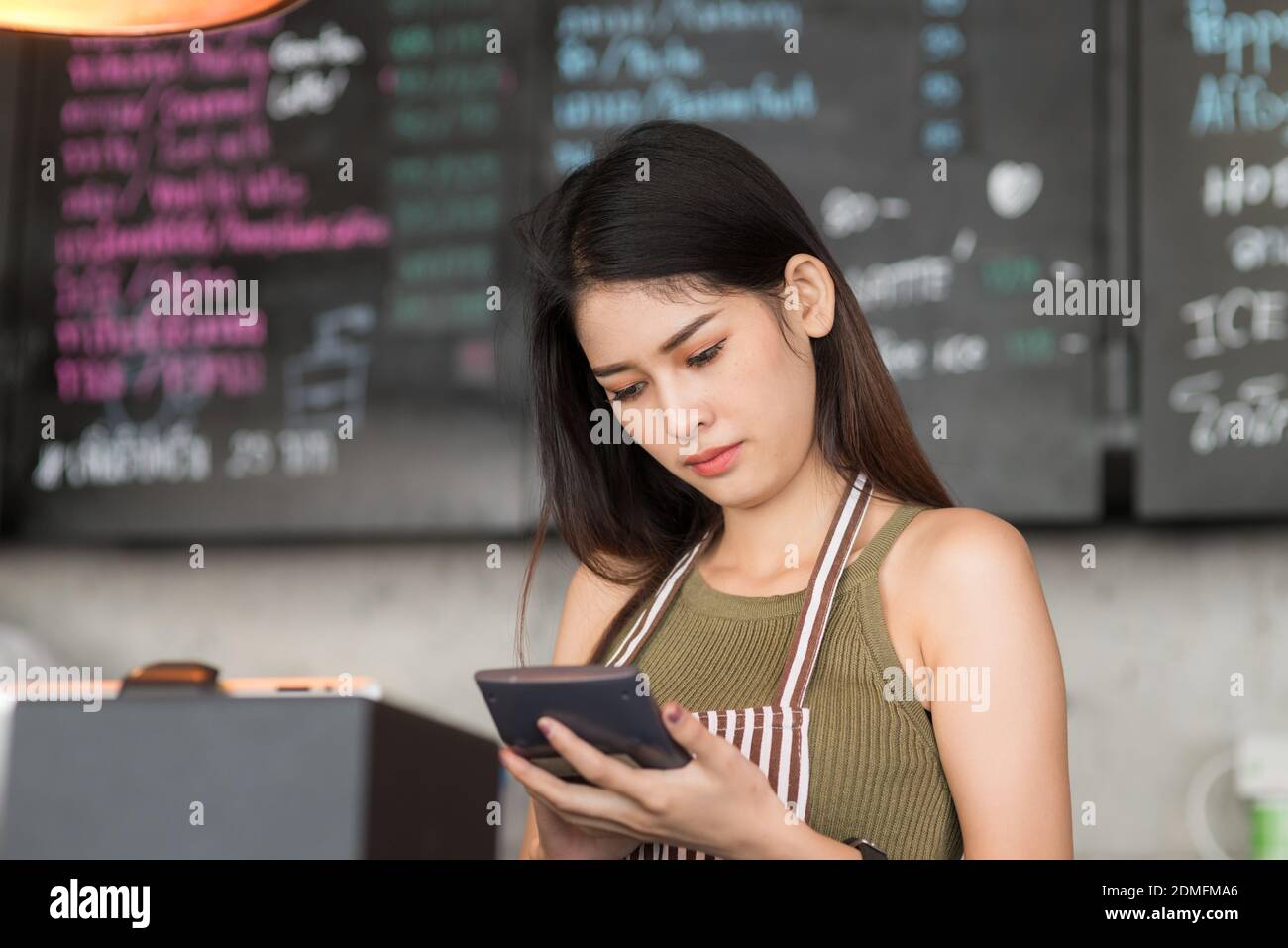 Female Owner Using Calculator At Cafe Stock Photo - Alamy