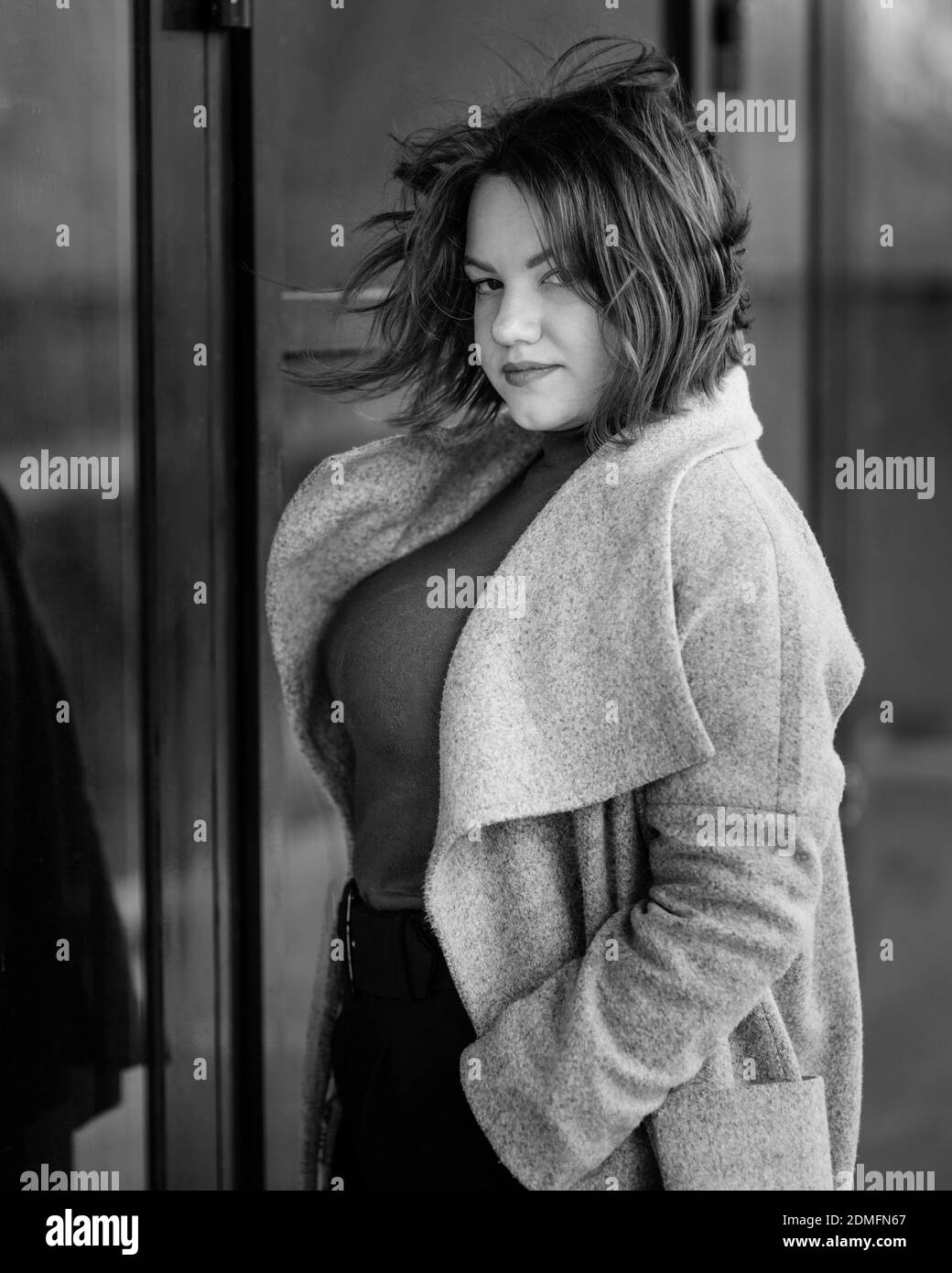 Brunette girl near wall on the street of city . Plus size model. Black and white Stock Photo