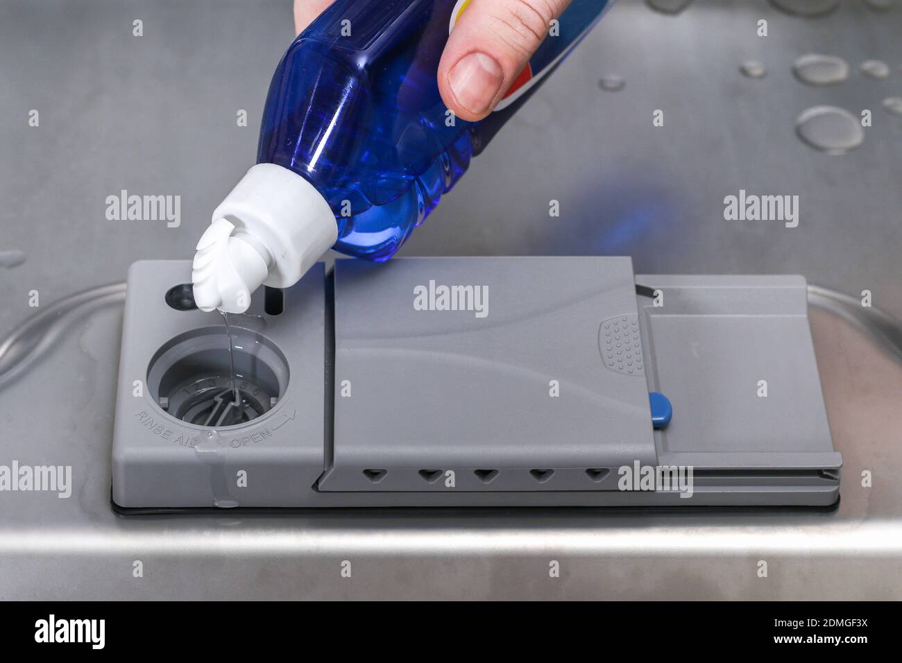 A man pours a rinse aid into the dishwasher compartment Stock Photo Alamy