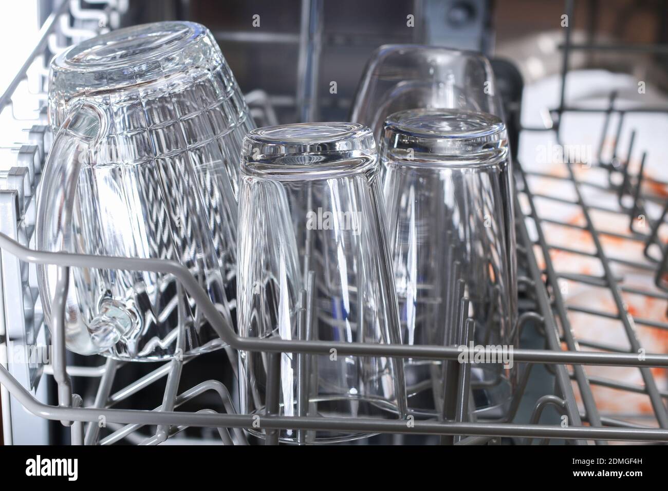 A man loads dirty dishes, plates, spoons, forks, cutlery into the dishwasher tray Stock Photo