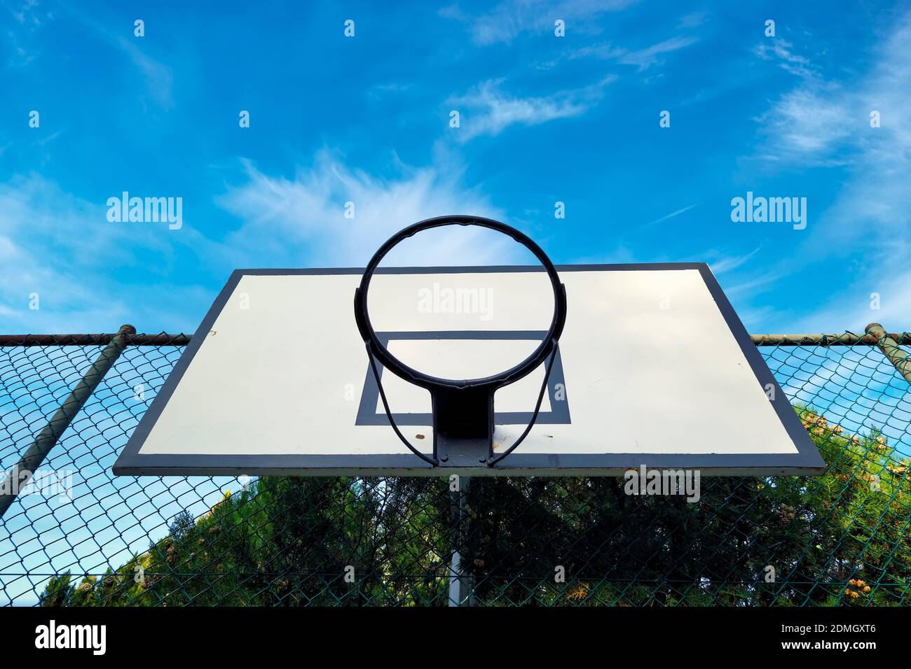 Outdoor basketball hoop in a court mounted on a fence wire against blue