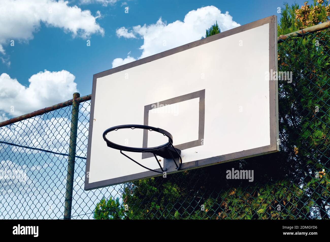 Outdoor basketball hoop in a court mounted on a fence wire against blue sky  background Stock Photo - Alamy