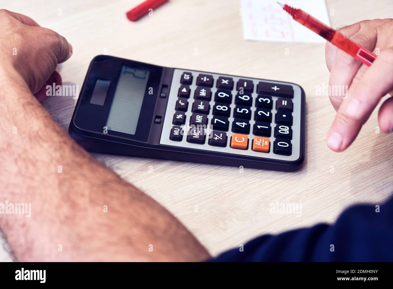 Businessman or accountant uses a calculator for financial tax or budget analysis on the office desk. Stock Photo
