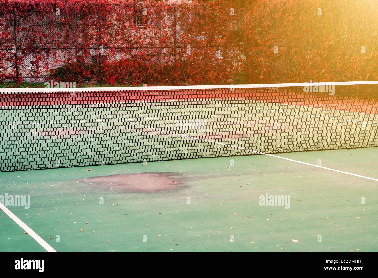 Worn clay or hard surface outdoor tennis court with net Stock Photo