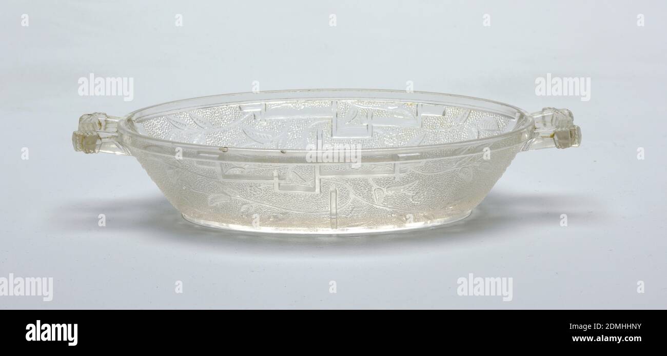 Dish, pressed glass, Of clear glass, the tapering oval form with simple slightly squared handles; outer surface of body molded with Japanese-inspired decoration of open flowers and flowing stems and leaves and fret work on a pebble-textured ground; underside of bottom with a regular pattern of squares., ca. 1880, glasswares, Decorative Arts, Dish Stock Photo