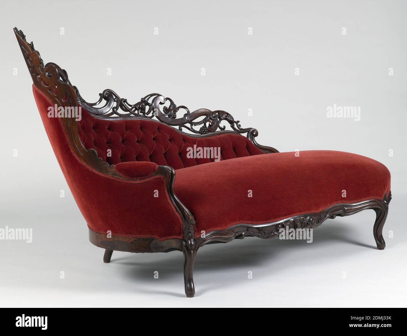 Chaise, Rosewood veneer, oak (frame), velvet upholstery, Serpentine front, rounded ends, cabriole legs fitted with castors; back of serpentine profile, raised high in circle at one end and crowned with pierced cresting of laminated wood in scrolls and acanthus shoots. Cluster of flowers in relief at center of arched back, and another at center of apron. Upholstered in contemporaneous machine-woven fancy compound satin, tufted on back., New York, USA, 1860–70, furniture, Decorative Arts, Chaise Stock Photo