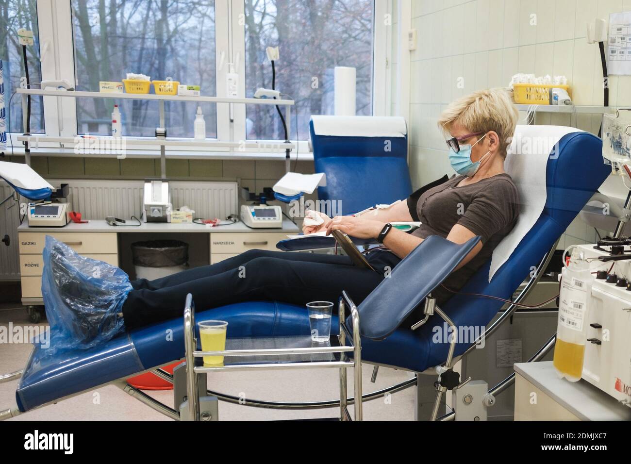 LUBIN, POLAND - DECEMBER 9, 2020. The woman with face mask donates blood plasma at the donation center. Plasma from convalescents is used to treat pat Stock Photo