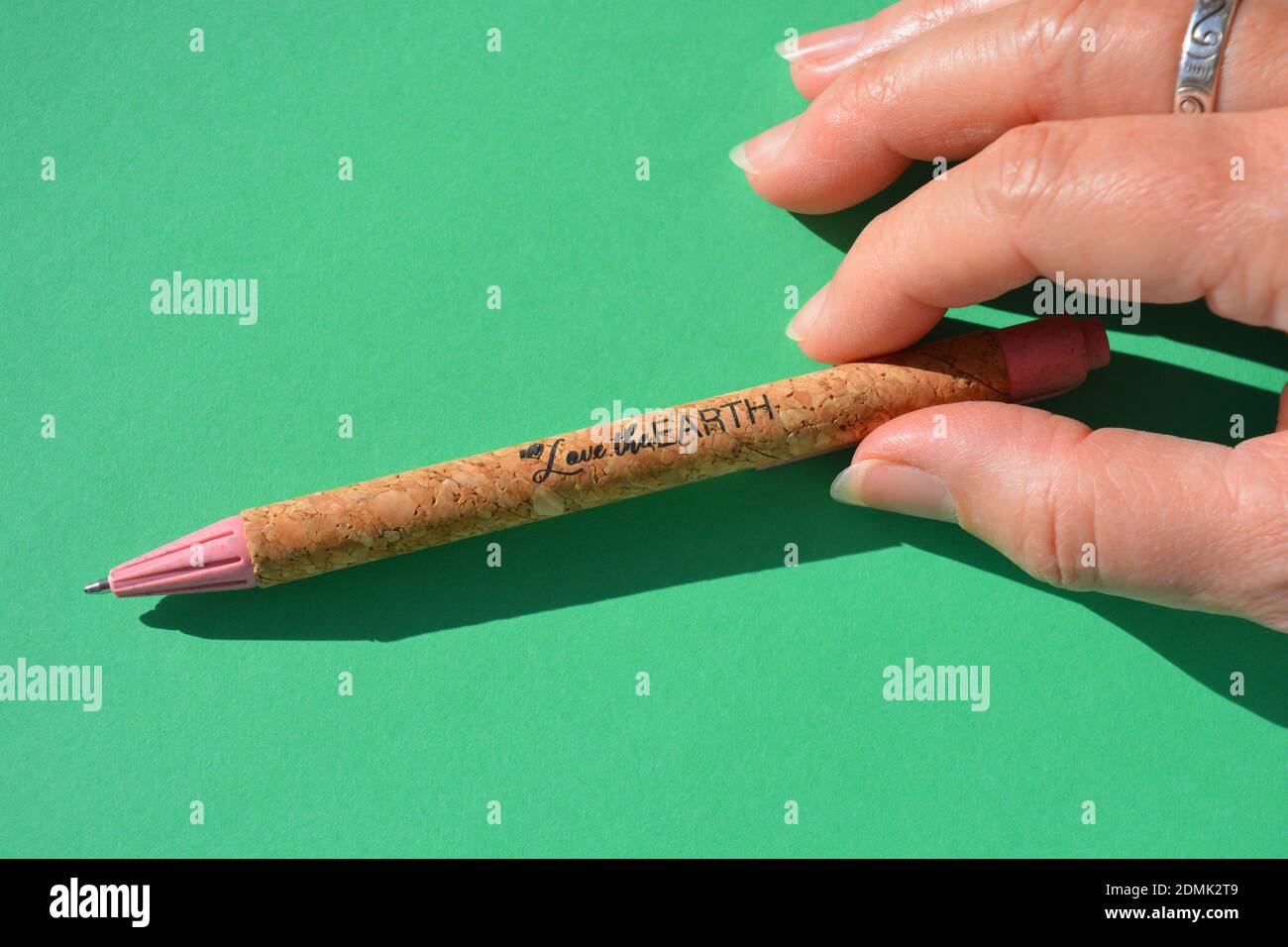 Love The Earth. Slogan On A Pen Made From Recycled Plastic And Sustainable Natural Cork. Pen In Hand Stock Photo