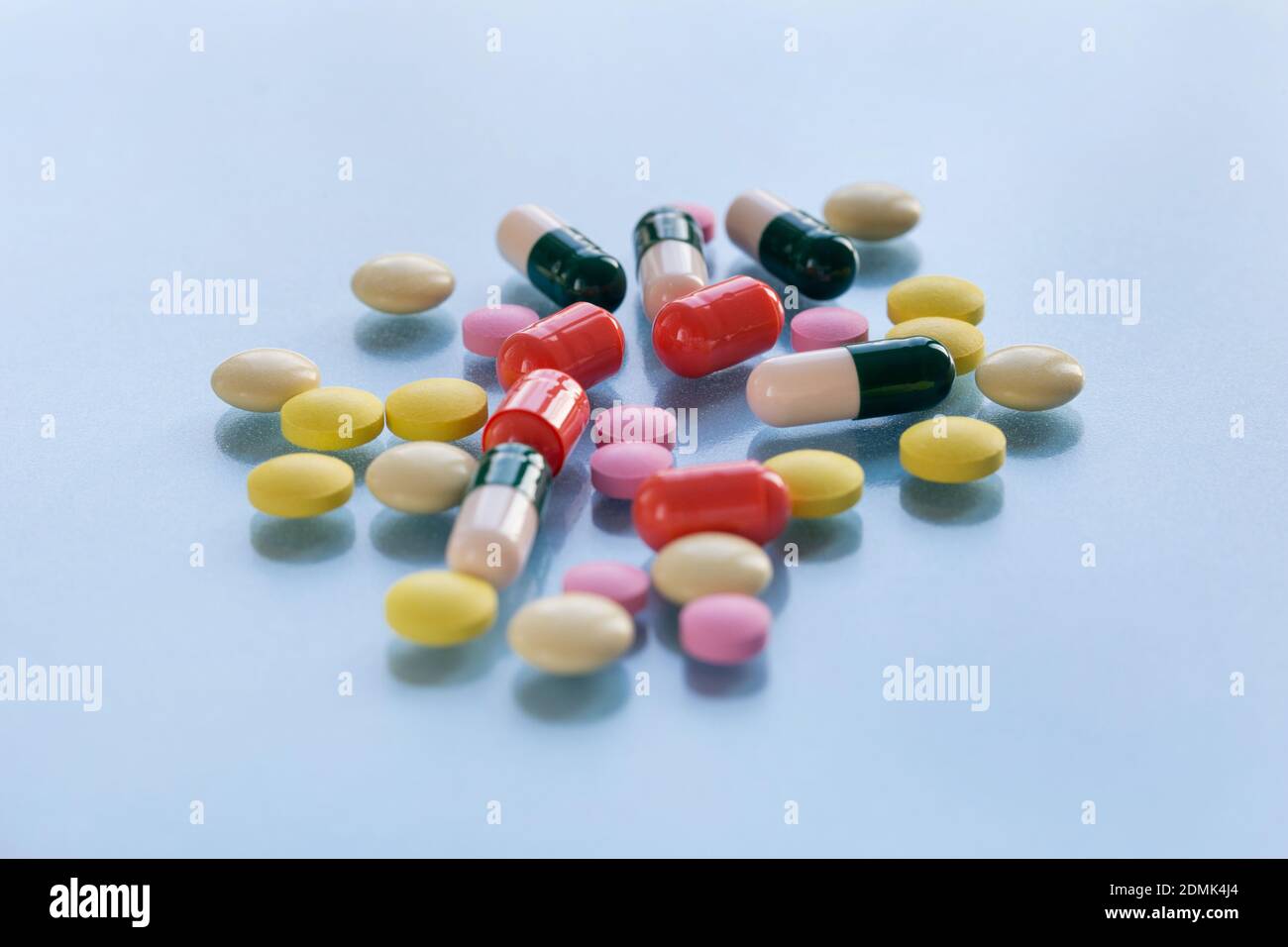 Colorful pills and capsules isolated on a blue background. Medical health or drugs addiction concept. Copy space for you text. Stock Photo
