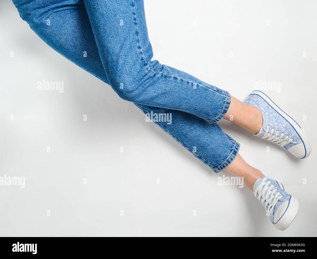 Female legs in jeans and sneakers on a white background. Top View Stock ...