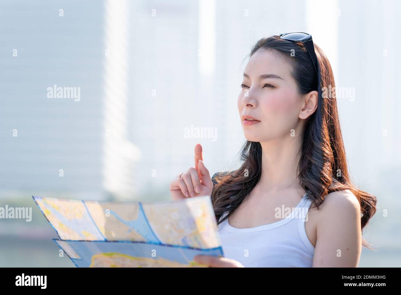 Beautiful asian tourist woman looking at map for searching location of landmark. Vacation travel in summer Stock Photo