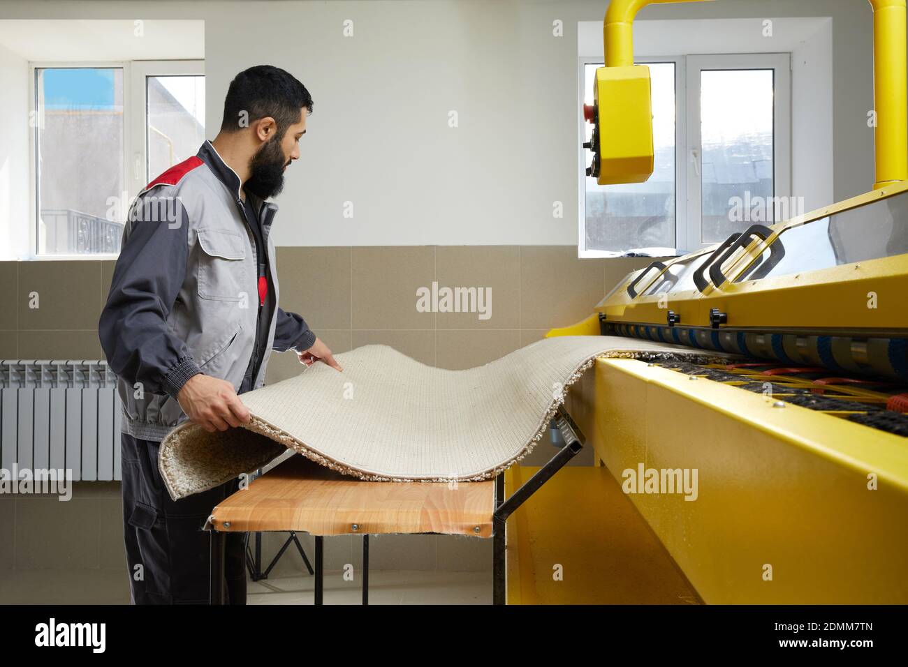 Man operating carpet automatic washing machine in professional laundry service Stock Photo