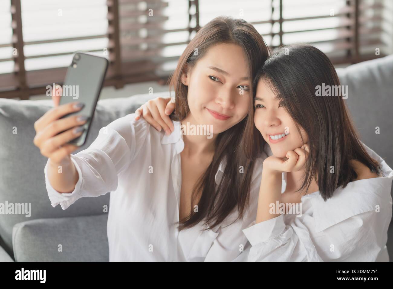 Two young female using mobile phone and internet technology to use video call to other friends during stay safe at home Stock Photo