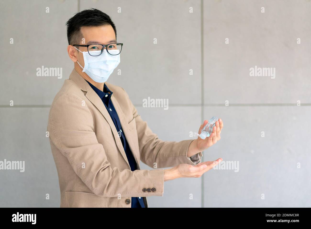 Business man wearing mask and using personal sanitizer to cleaning his hand in office to keep hygiene.Preventive during the period of epidemic from co Stock Photo