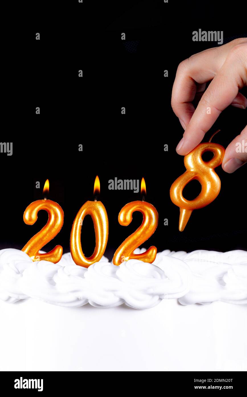 Four golden candles write numbers flame happy new year 2028 hand black background Stock Photo