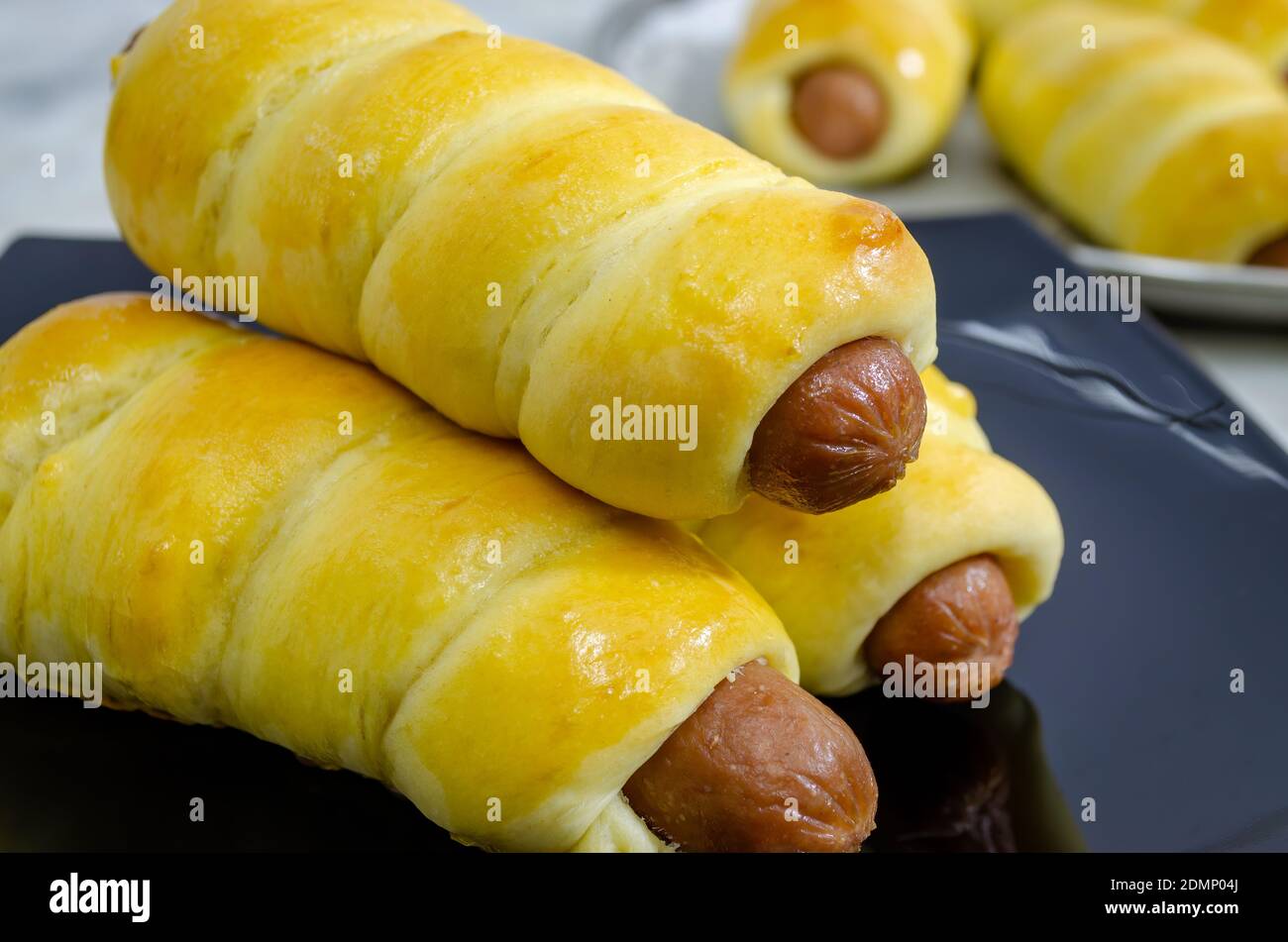 Closeup of freshly baked and stacked Sausage Rolls on a black plate Stock Photo