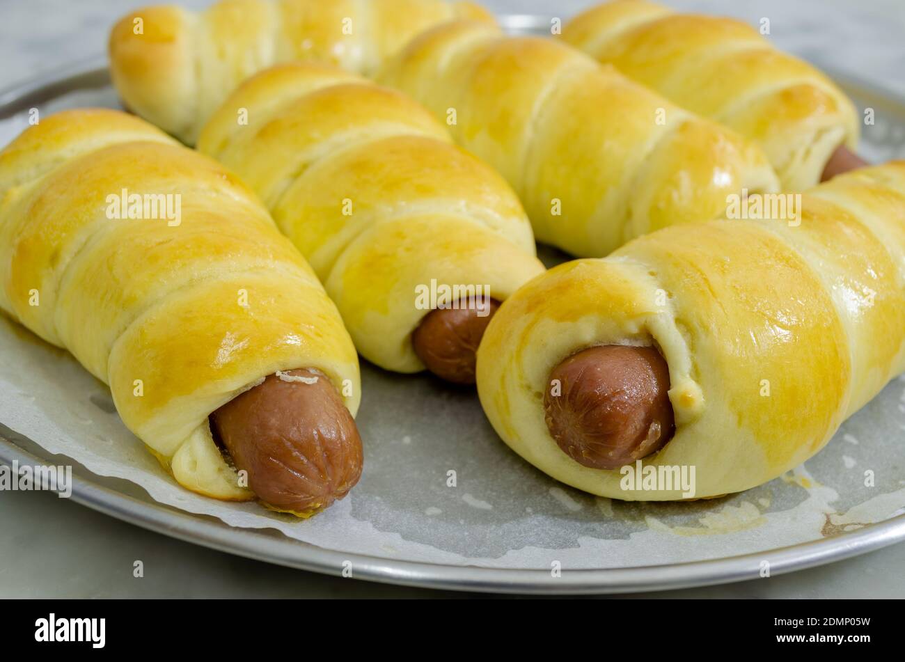 Closeup of freshly baked Sausage Rolls in a round steel plate Stock Photo