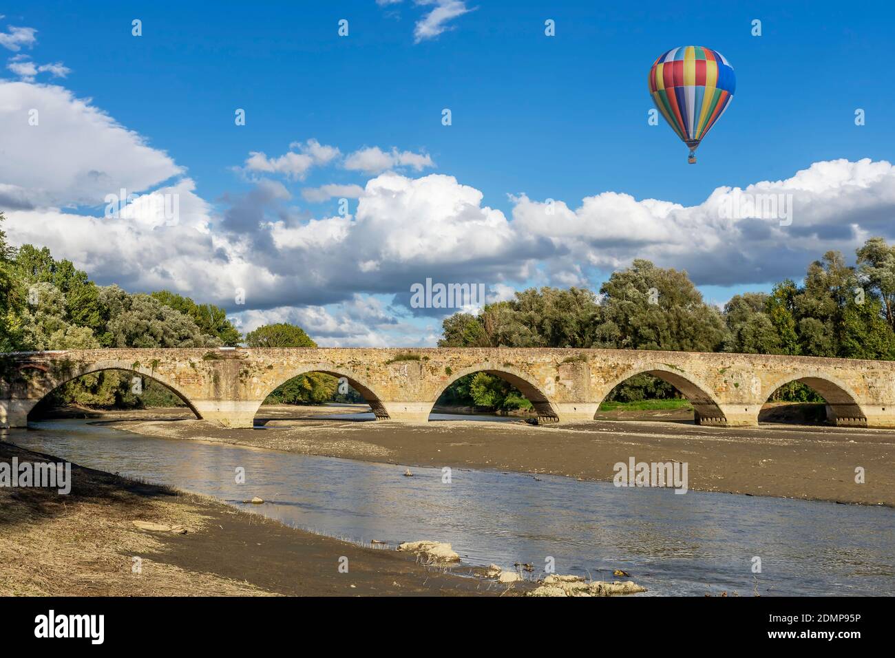 A colorful hot air balloon flies over the ancient Buriano Bridge, Arezzo, Italy Stock Photo