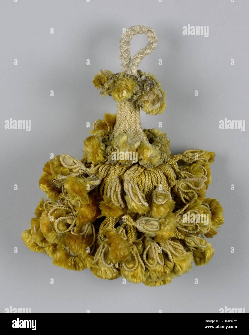 Tassel, Medium: silk, copper wire, linen, wooden core, Skirt of yellow silk threads in two lengths, twisted and looped and holding ornamental tassels. Two collars of similar tassels. Head, cylindrical and broadening toward the base, is wrapped in yellow threads. Loop of white silk threads braided into a cord., Spain, 18th century, trimmings, Tassel Stock Photo