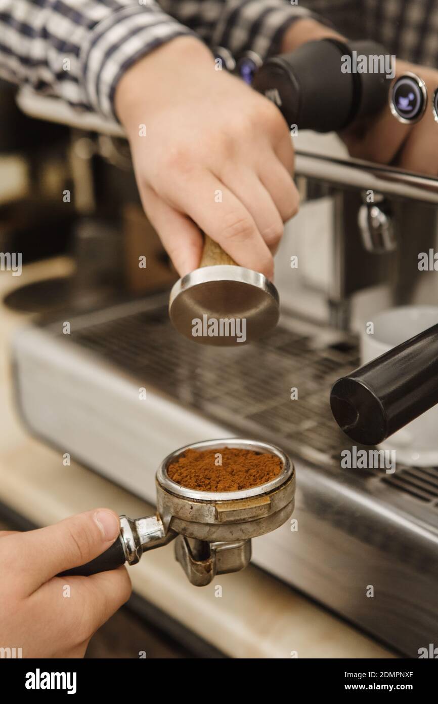 Vertical cropped shot of a barista preparing coffee using tamper for