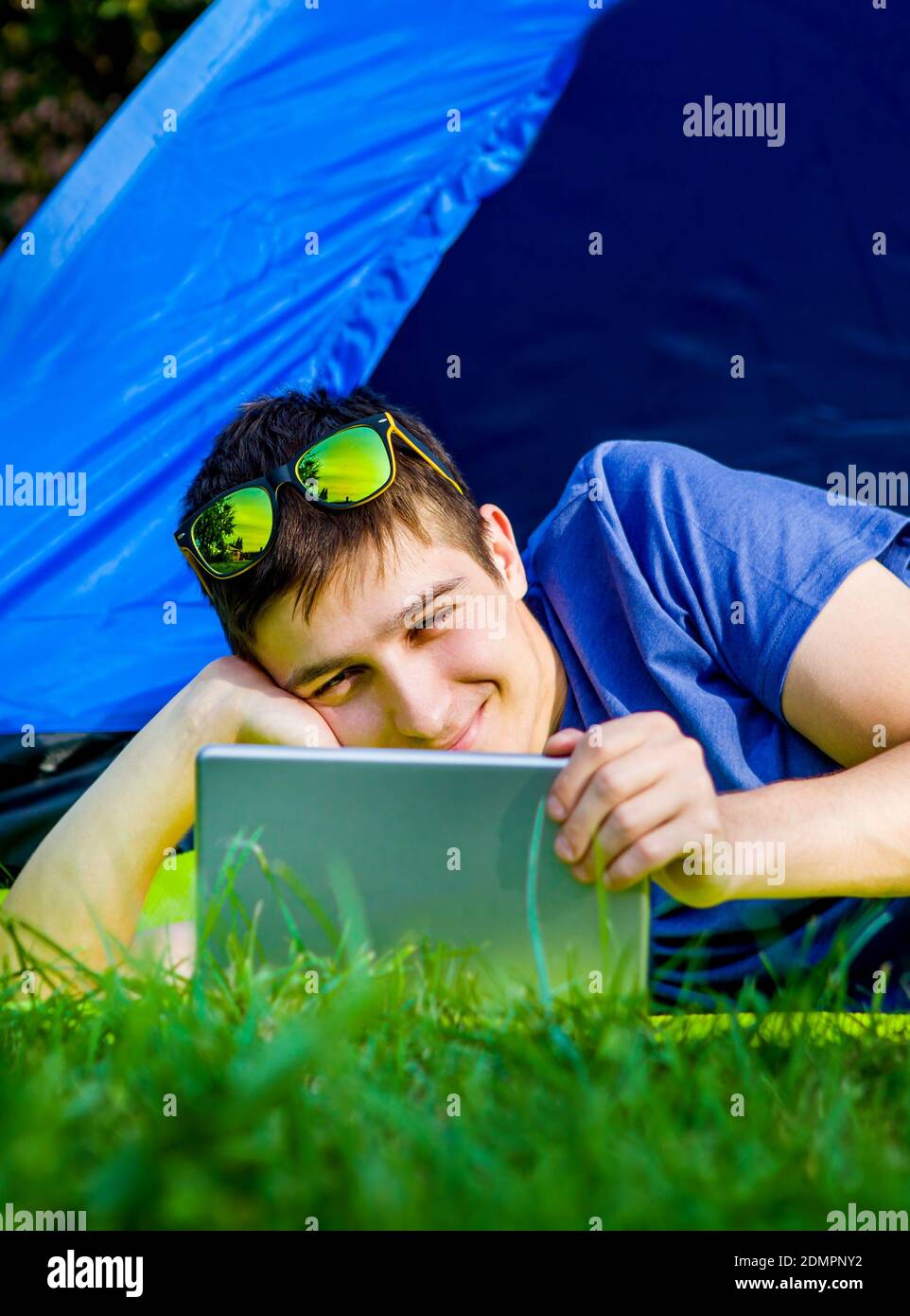 Young Man with a Tablet Computer in the Tent on the Nature Stock Photo