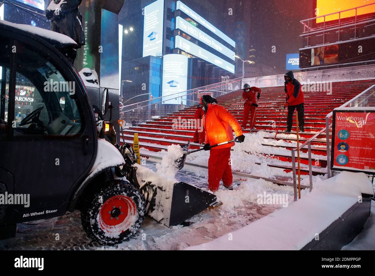 Times Square workers remove snow from the 'Red Steps' as major snow storm of 2020 brings over 7 inches of snow in just a few hours. As the nor’easter descends upon New York City, temperatures hover near 30 degrees, and wind gusts of up to 30 mph sweep the city. Stock Photo