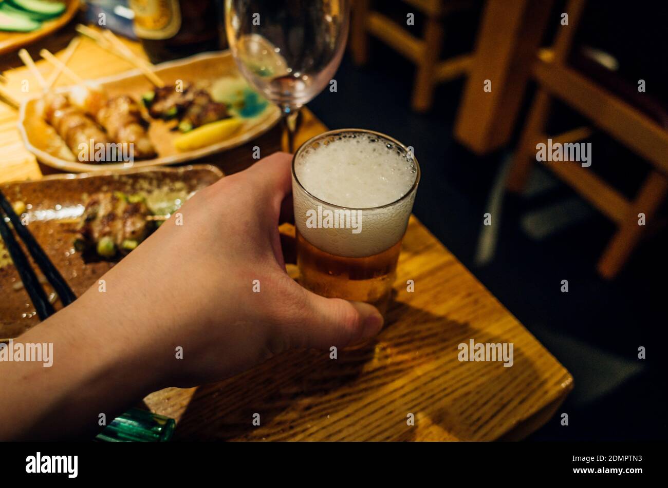 Cropped Hand Holding Beer Glass On Restaurant Table At Night Stock Photo Alamy