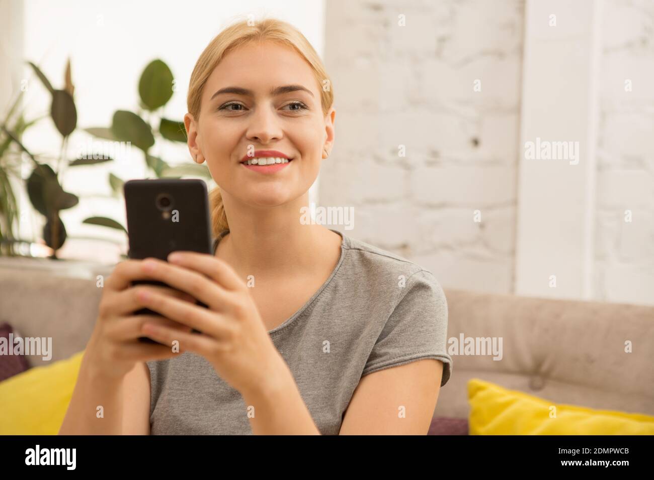 Young attractive woman smiling looking away while texting on her smart ...
