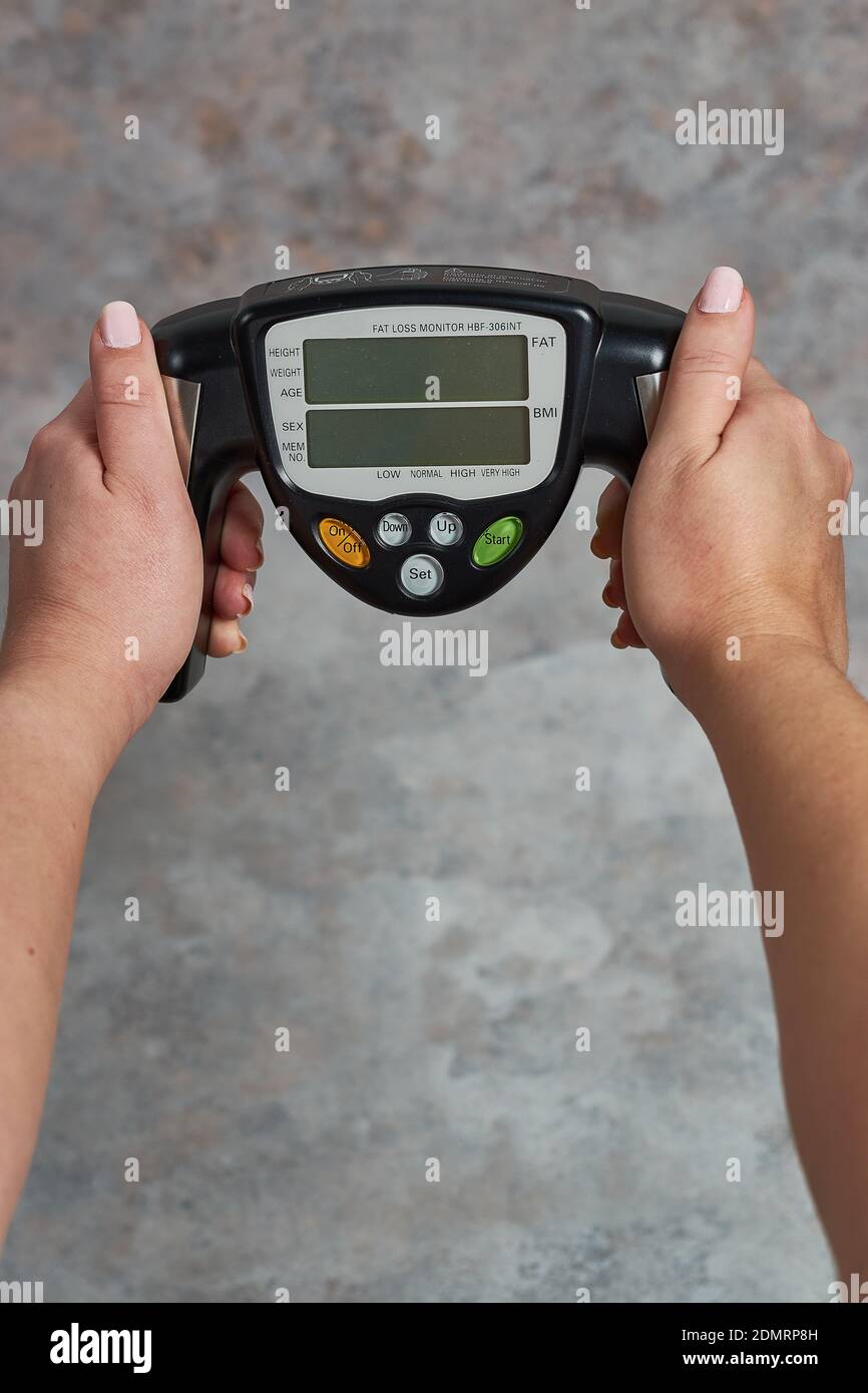 https://c8.alamy.com/comp/2DMRP8H/a-female-holding-a-fat-loss-monitor-a-grunge-background-2DMRP8H.jpg