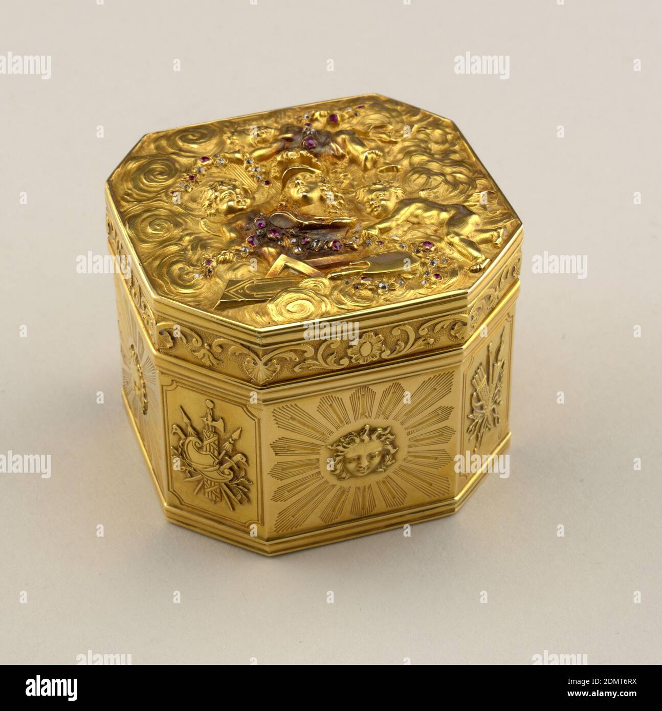 Box, Gold, diamonds, rubies, Tooled gold, cubic shape, chamfered corners. Hinged lid with helmeted bust on cloud-like background surrounded by three flying cherubs bearing diamond and ruby studded garlands; T-square, palette, brushes, drawing at base of bust. Each side of box decorated with rayed head; trophies on each chamfered corner., France, 1750–56, containers, Decorative Arts, Box Stock Photo