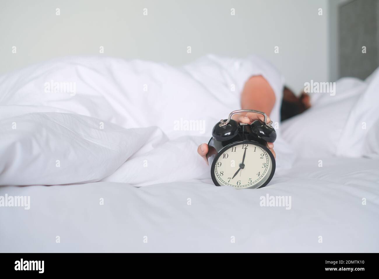 Woman Holding Alarm Clock While Sleeping On Bed Stock Photo Alamy
