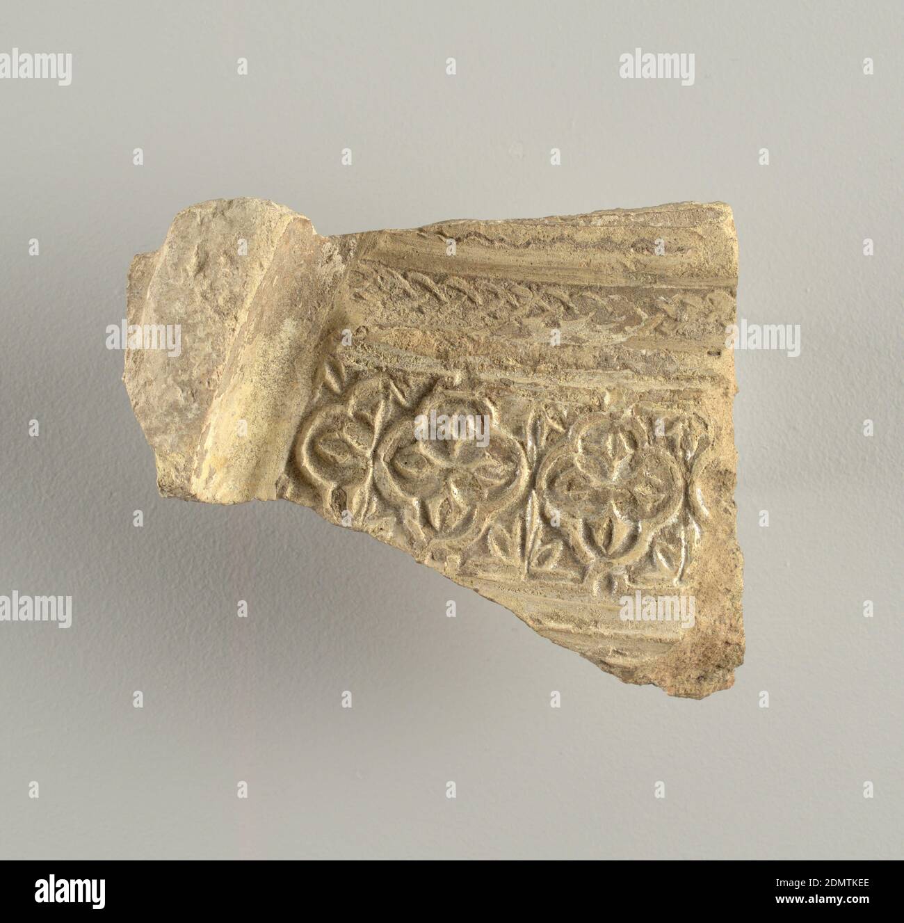 Pot sherd, tin-enamelled earthenware, Irregular fragment with flanged edge and ornament in relief consisting of quatrefoil and chain motifs surmounting an incised wavy line. Pearly iridescence., Seville, Spain, 14th–16th century, tiles, Decorative Arts, Pot sherd Stock Photo
