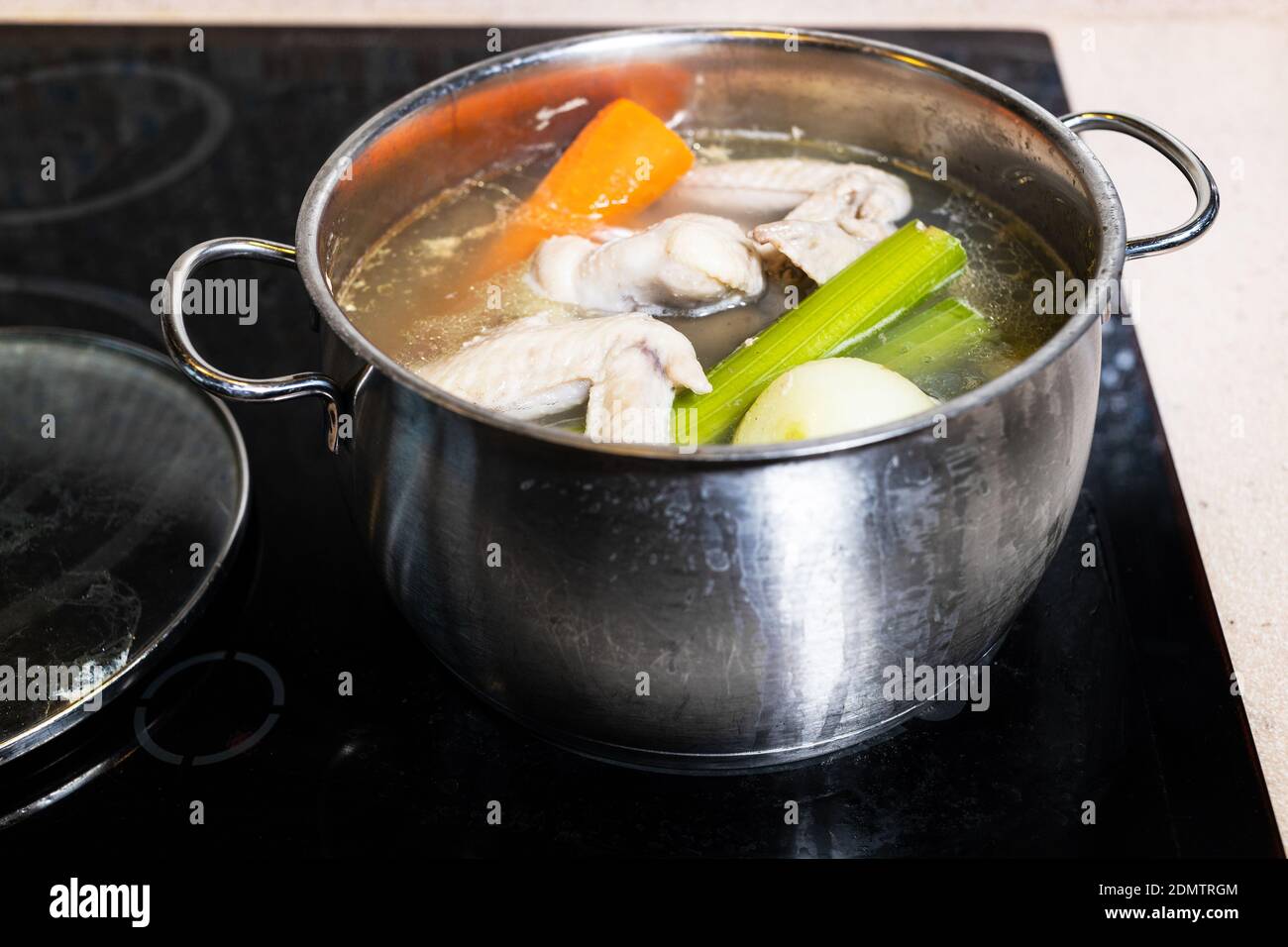 chicken wings soup is boiled in steel stewpot on stove at home kitchen isolated on white background Stock Photo