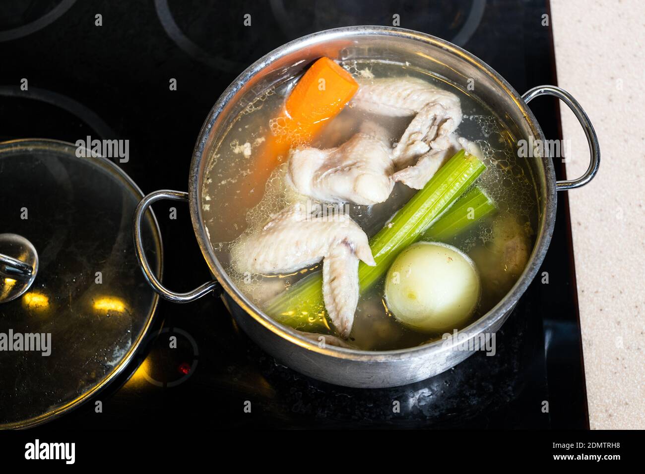 top view of chicken wings broth is cooked in steel stewpot on stove at home kitchen isolated on white background Stock Photo