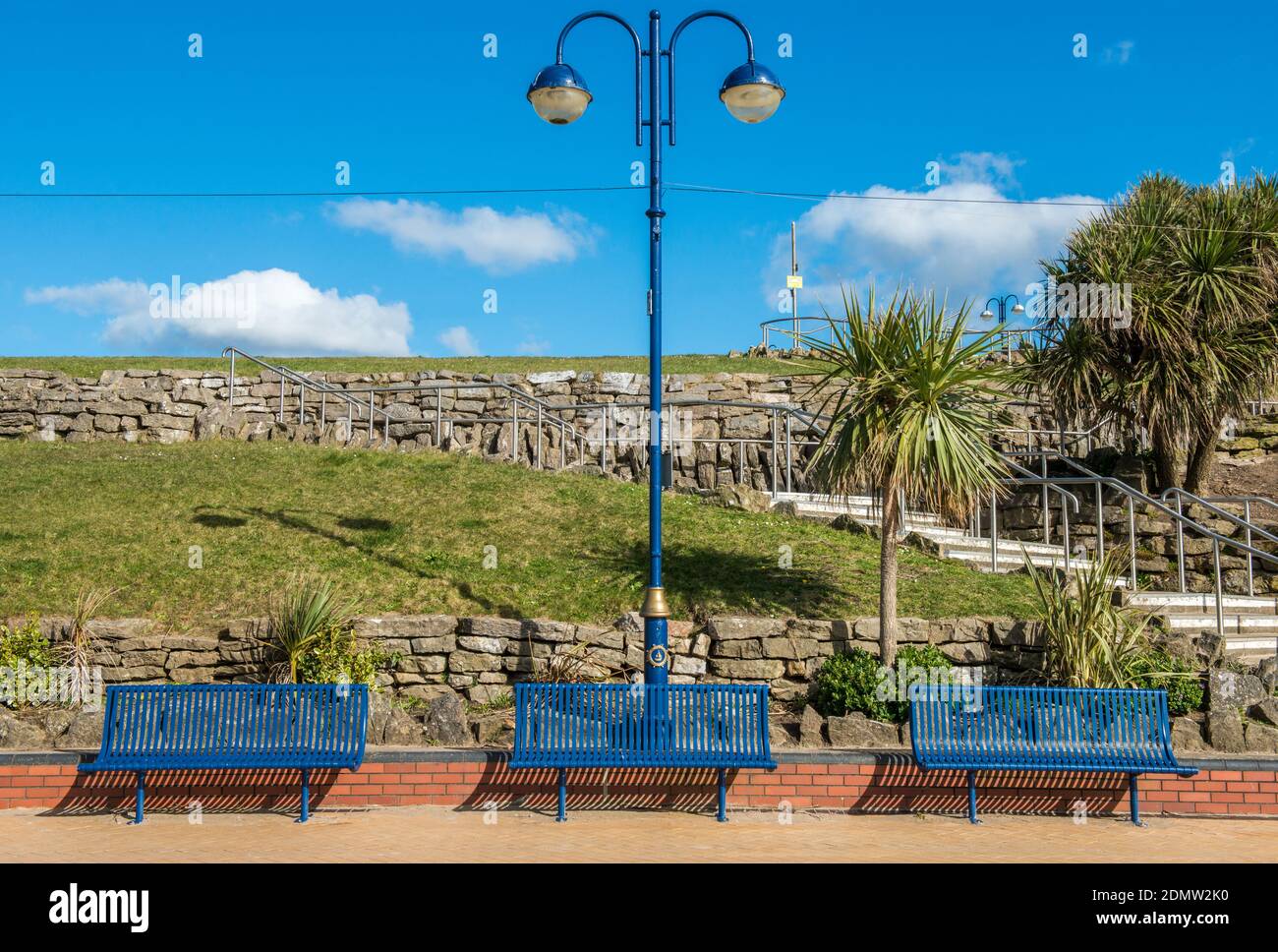 Three Blue Benches and a street light adorn Whitmore Bay on Barry Island in south Wales. Stock Photo