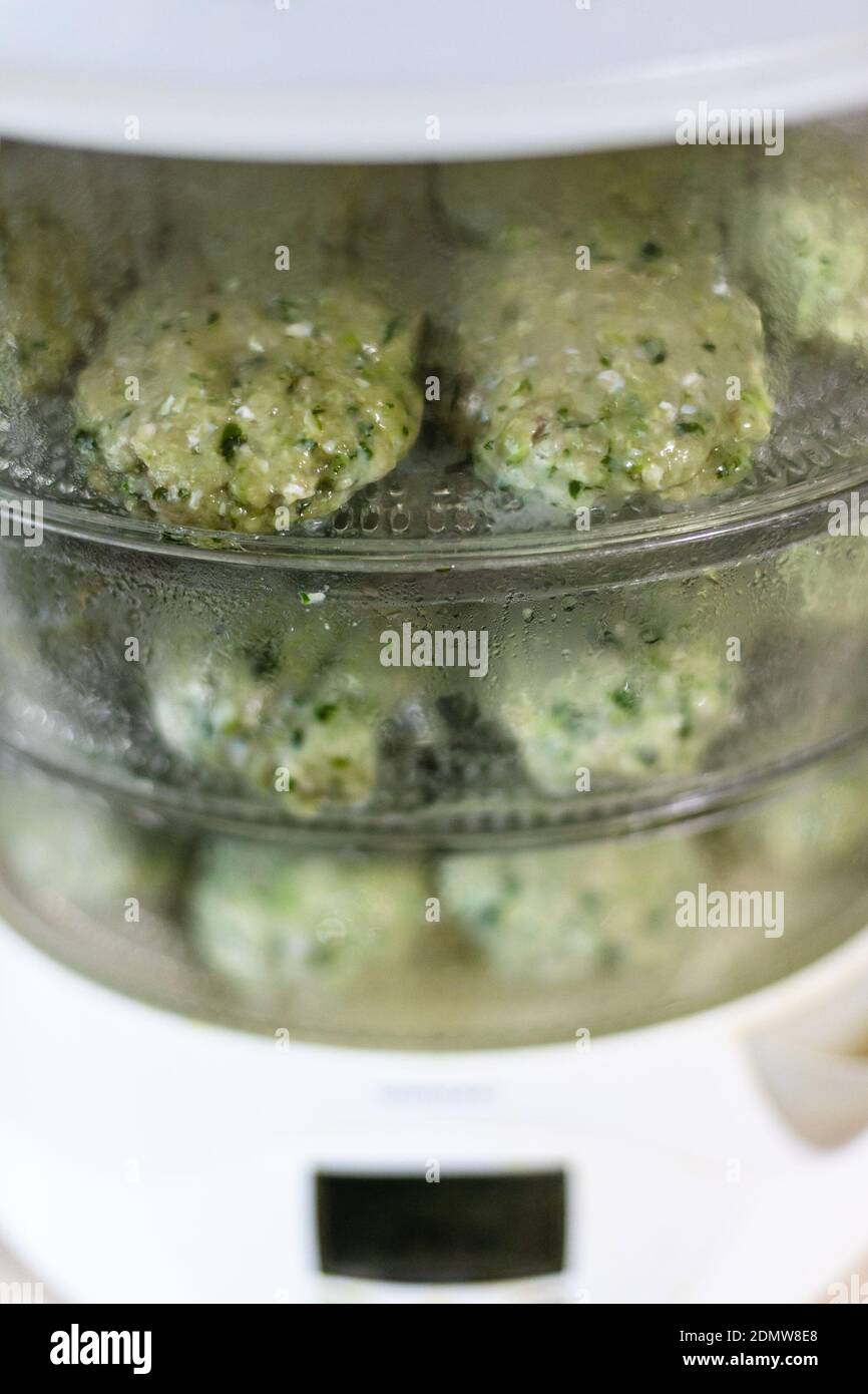 electric steamer with cooking cutlets from turkey meat and greens at