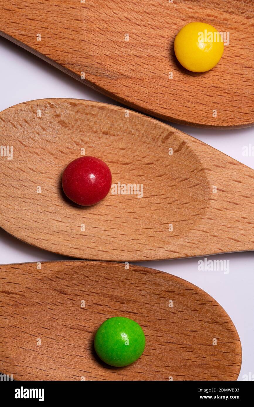 Wooden spoons on white background with red, yellow, green candy Stock Photo