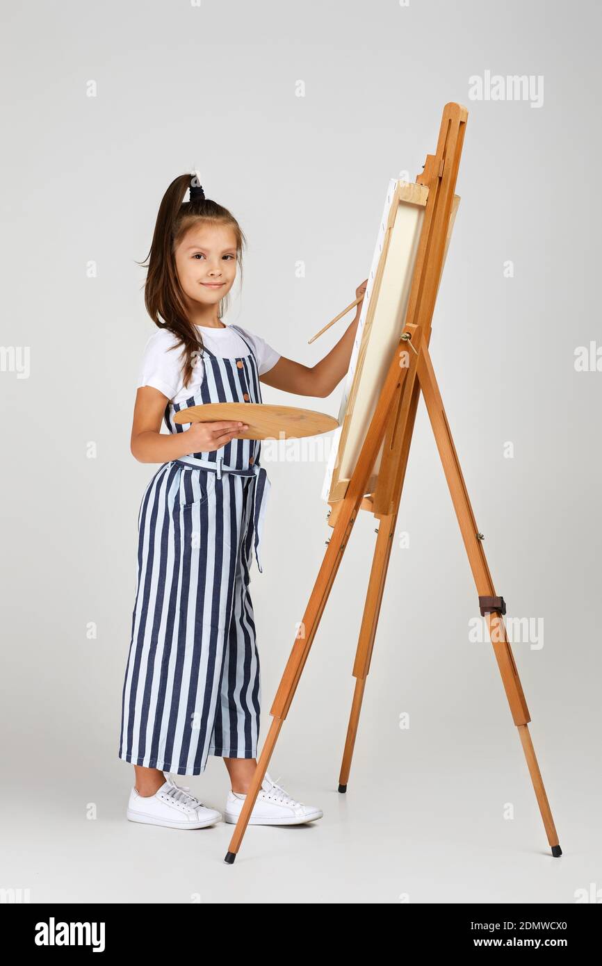 cute little girl holding a wooden art palette and brush on studio ...