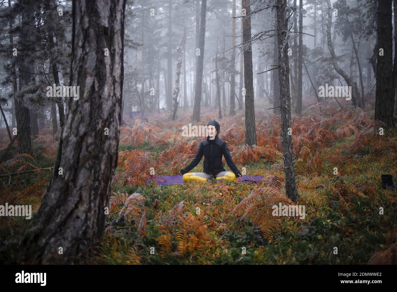 Woman meditating in woodland setting, morning yoga in the forest