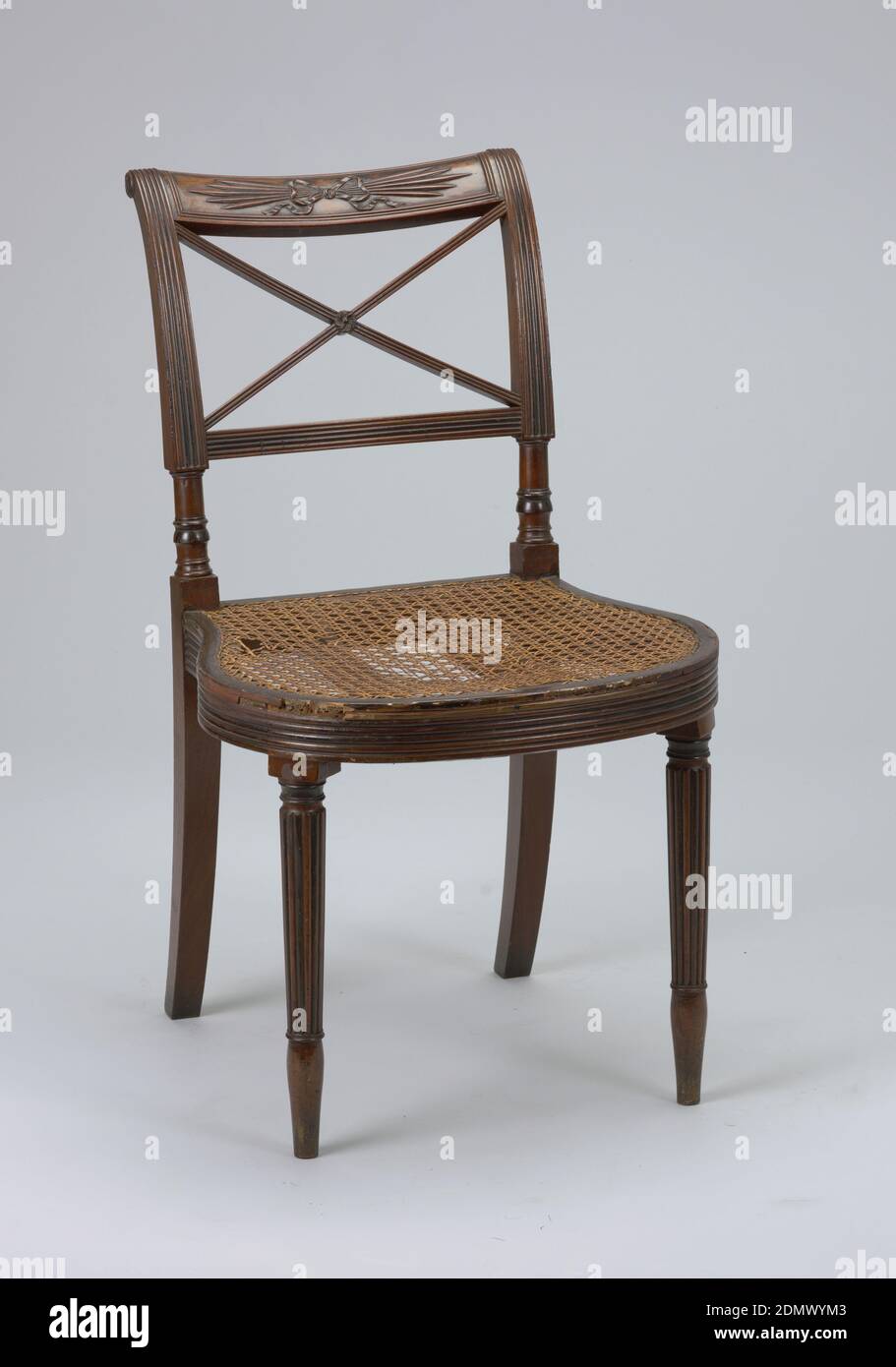 Side chair, mahogany caned seat covered with upholstery, Rounded and reeded seat rail; rounded and reeded tapering legs. Top rail carved with 'thunderbolt design,' tied with bow. Below top rail, two diagonal, crossing bars, reeded., New York, USA, ca. 1812, furniture, Decorative Arts, Side chair Stock Photo