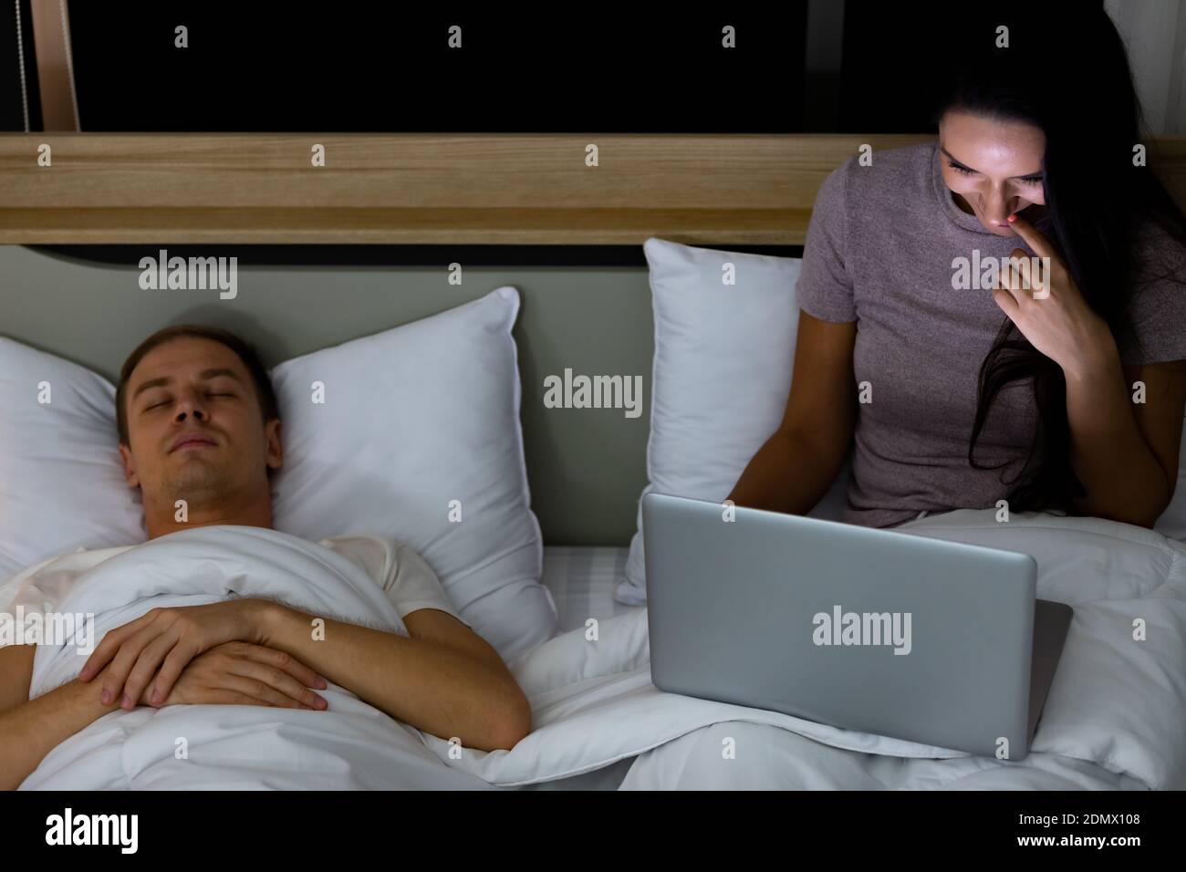 Woman sitting on bed in the night and using laptop computer while