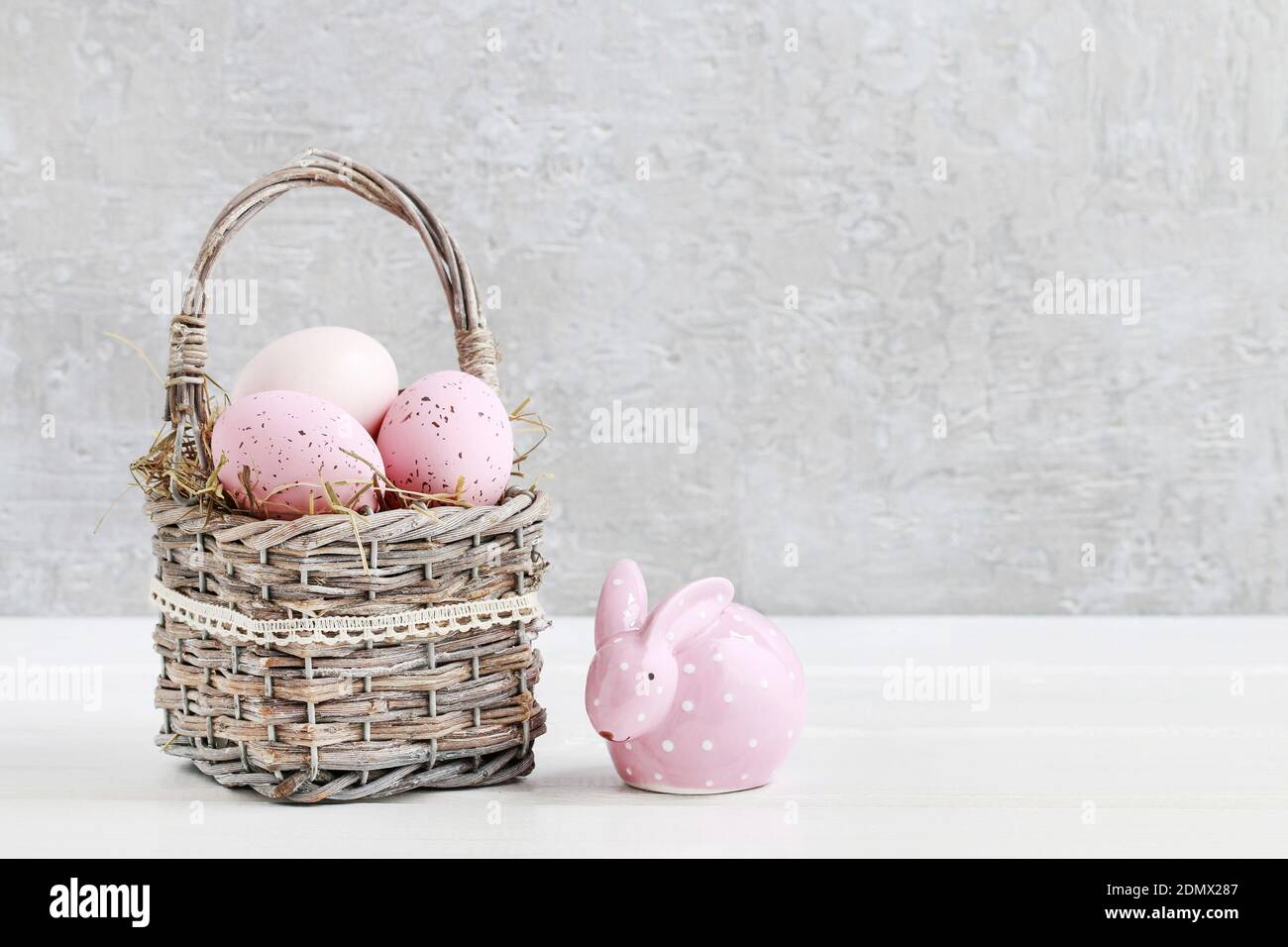 Wicker basket with Easter eggs and ceramic rabbit figure on white ...