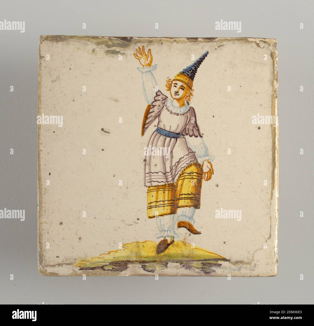 Tile, Earthenware, glazed and high fire decorated, Dancing man, dressed in white pantelettes, yellow skirt, white and manganese overshirt, and wearing pointed blue, brimless hat. Chinoiserie type of decoration ., Alcora, Spain, late 18th–early 19th century, tiles, Decorative Arts, Tile Stock Photo